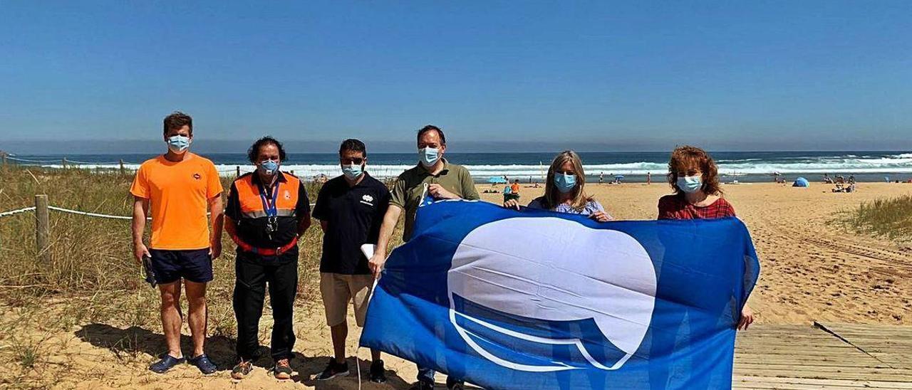 Ramón Piñuli, socorrista; Teo Morís, coordinador de Protección Civil; Borja Madiedo, coordinador de salvamento; Alejandro Vega, alcalde de Villaviciosa; Graciela Blanco, viceconsejera de Turismo; y Lorena Villar, concejala de Medio Ambiente, durante el izado de la bandera azul en la playa de Rodiles.