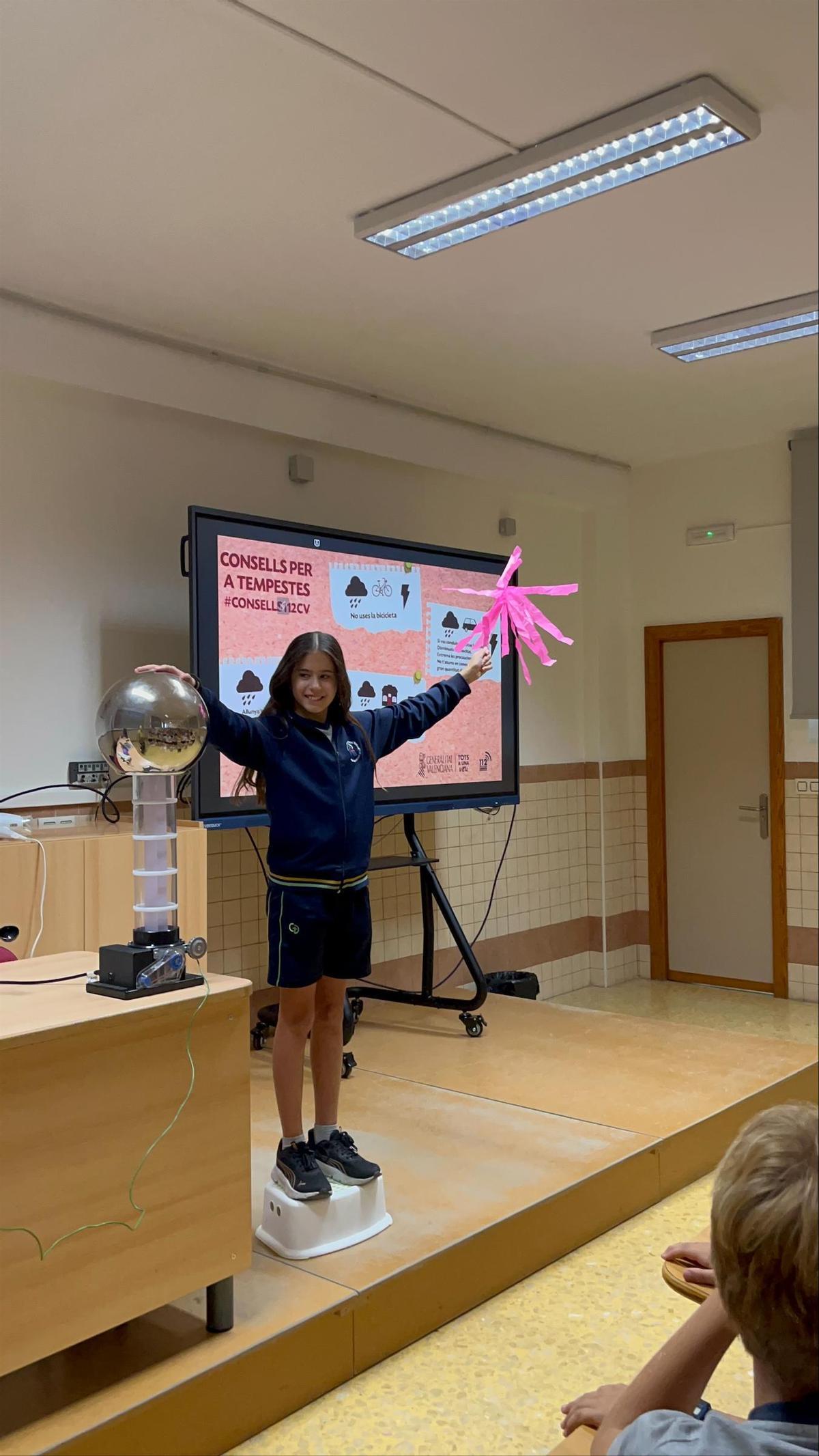 Una xiqueta comprova l’energia electroestàtica que emet un generador Van de Graaff en una sessió de 'MeteoAula' a Riba-roja.