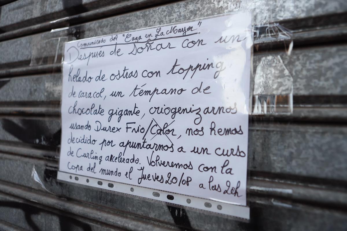 Cartel anunciando el cierre por vacaciones en la puerta del bar El Caza en La Mayor, en la calle Mayor.