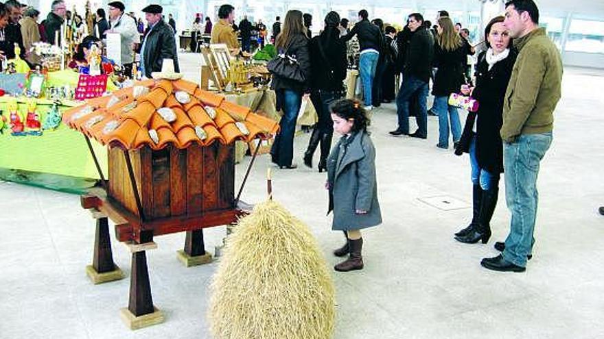 Una niña observa un hórreo en la Feria de Artesanía de la Pola.