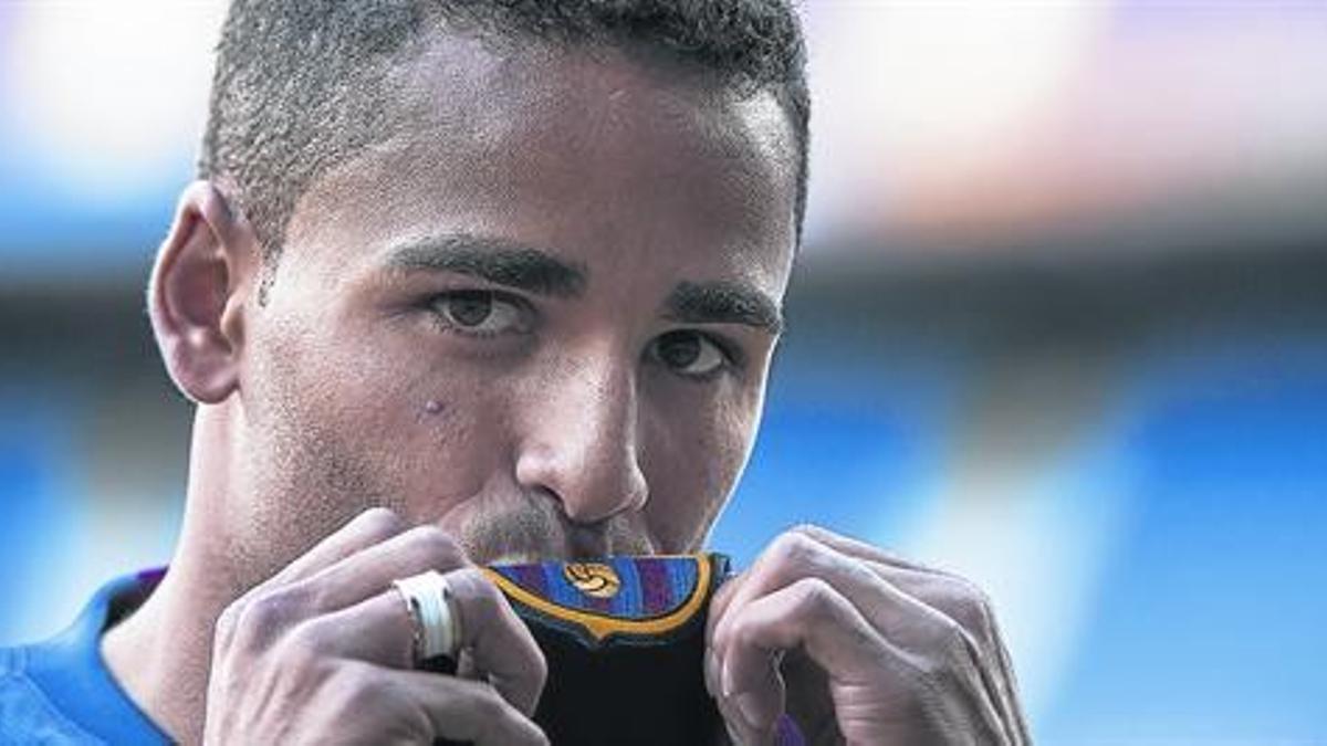 Douglas besa el escudo durante su presentación en el Camp Nou, ayer.