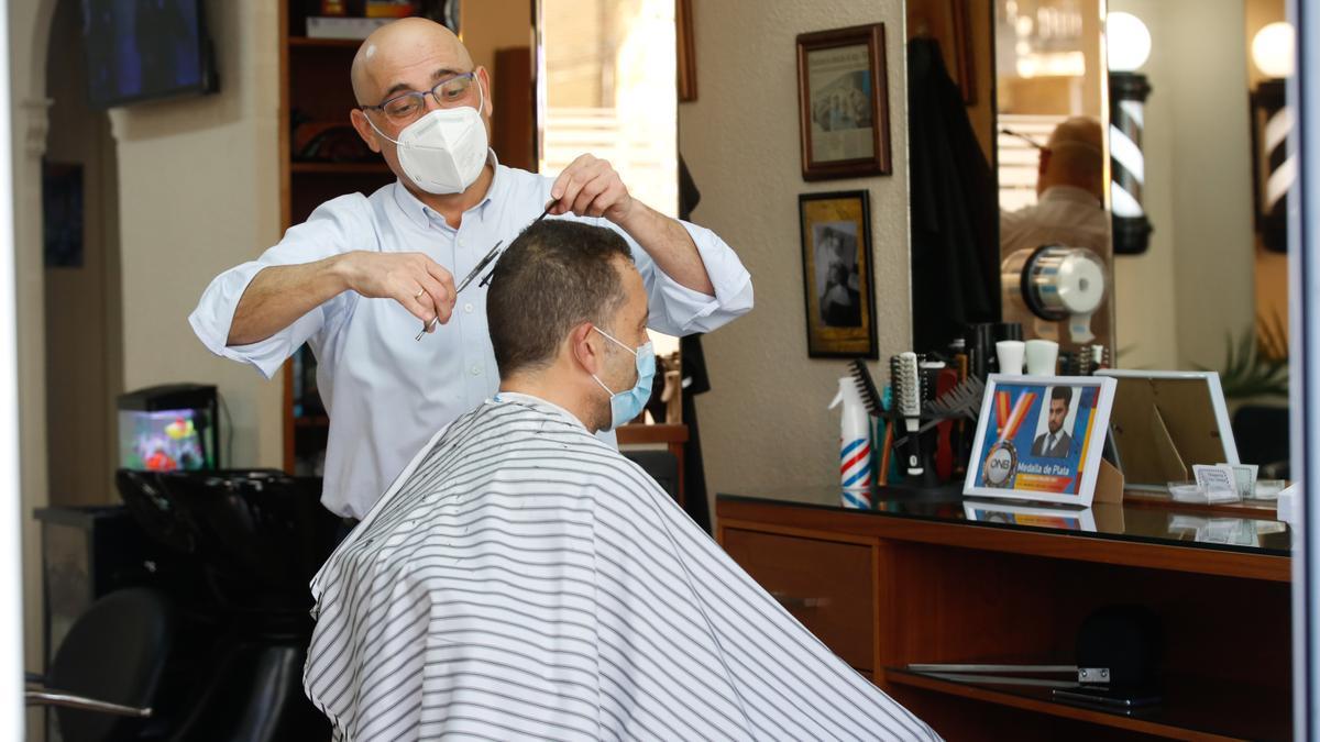 El peluquero, Paco Molina, cortando el pelo a un cliente.