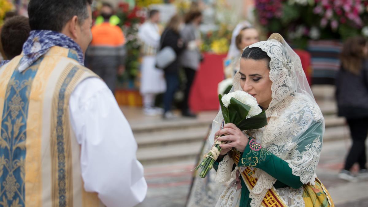 Una fallera entrega un ramo de claveles blancos.