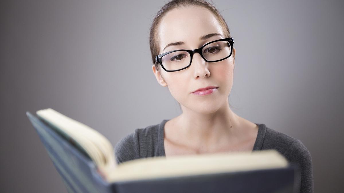 Una mujer con gafas lee un libro