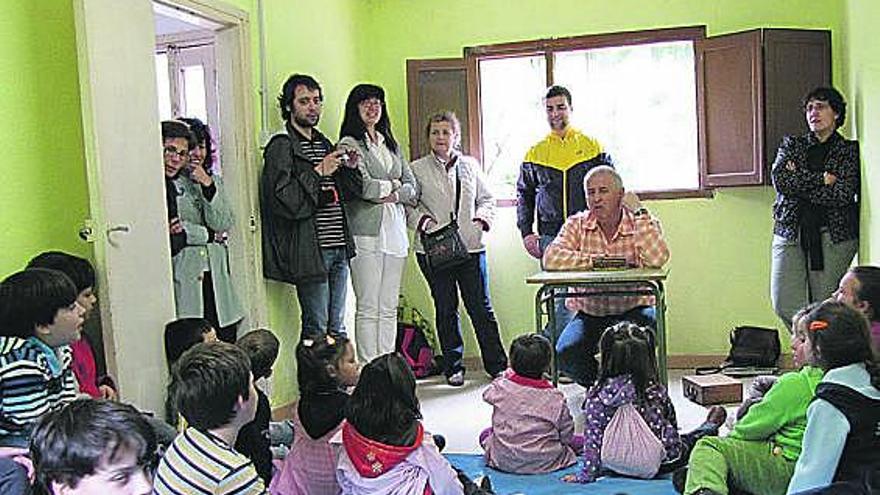 Fernando Maestro, sentado en un pupitre, con los alumnos del colegio rural agrupado de Naviego.