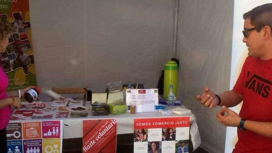 Arriba, el expositor que Cáritas presentó en la Feria Multicultural de septiembre, con productos de comercio justo y abajo una técnico de Cáritas Benavente colocando productos del punto de venta.