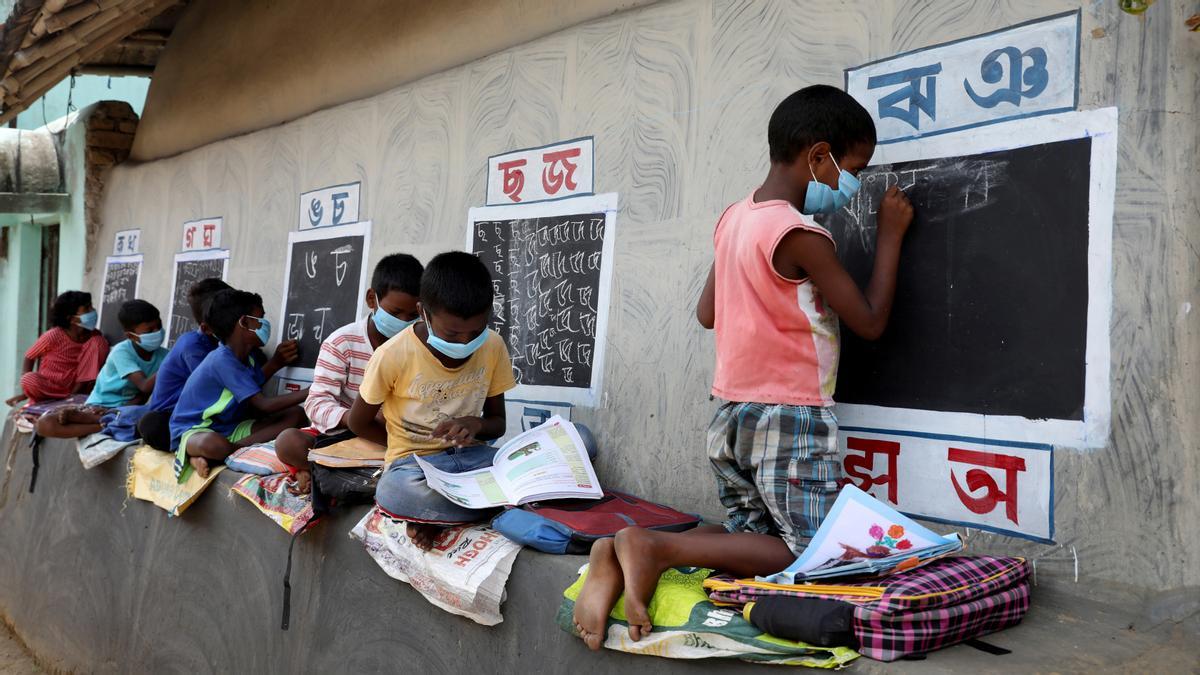 Los niños, que no tienen acceso a instalaciones y dispositivos de Internet, asisten a una clase al aire libre en Bengala Occidental, India