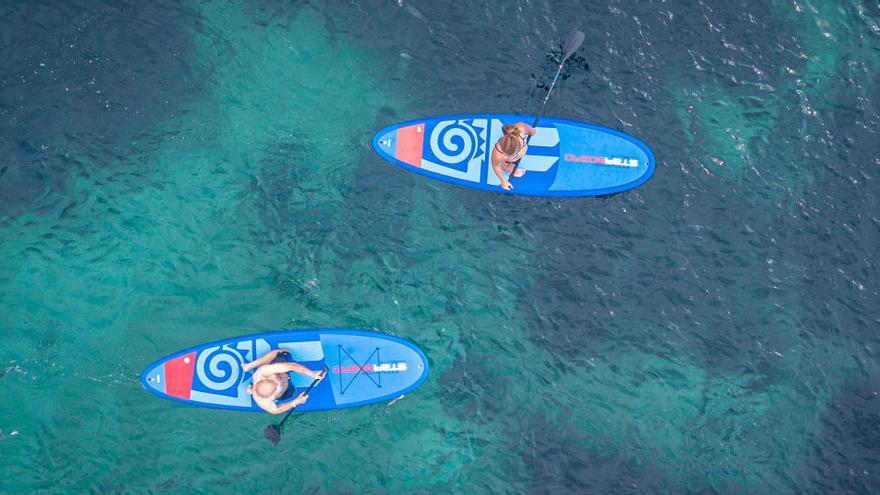 Dos deportistas practican padel surf.