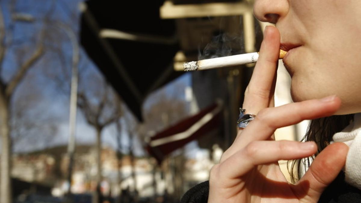 Una mujer fuma en la calle.