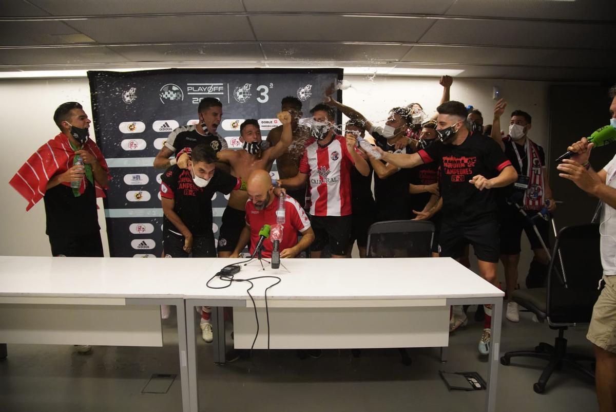 David Movilla es regado con champán por sus jugadores del Zamora CF durante la rueda de prensa tras el ascenso a Segunda B.
