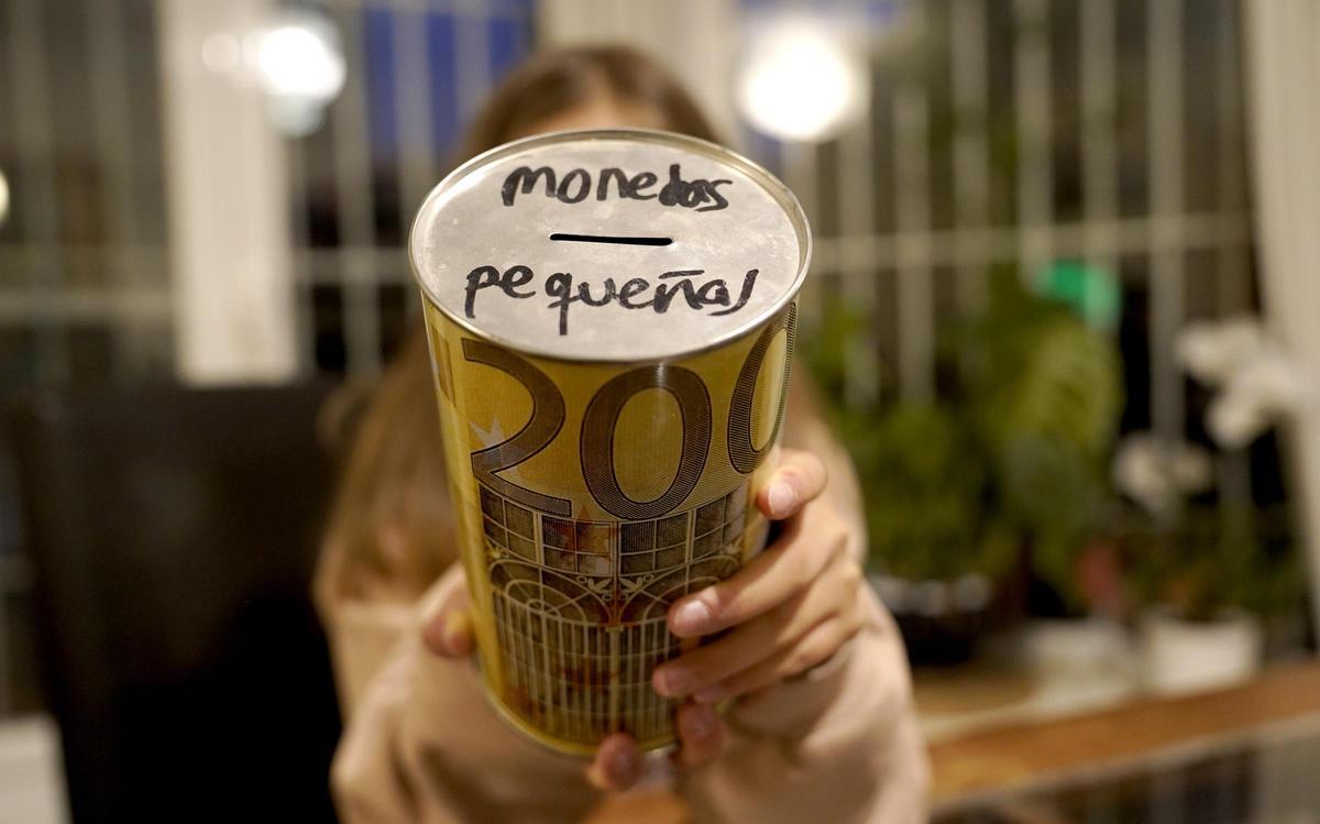 Una adolescente, en su casa de Madrid, muestra la hucha que le regalaron sus padres para ahorrar.