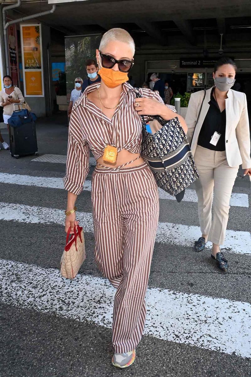 Iris Law a su llegada a Cannes con look de Mango con pantalones y camisa a rayas y pelo corto rubio platino