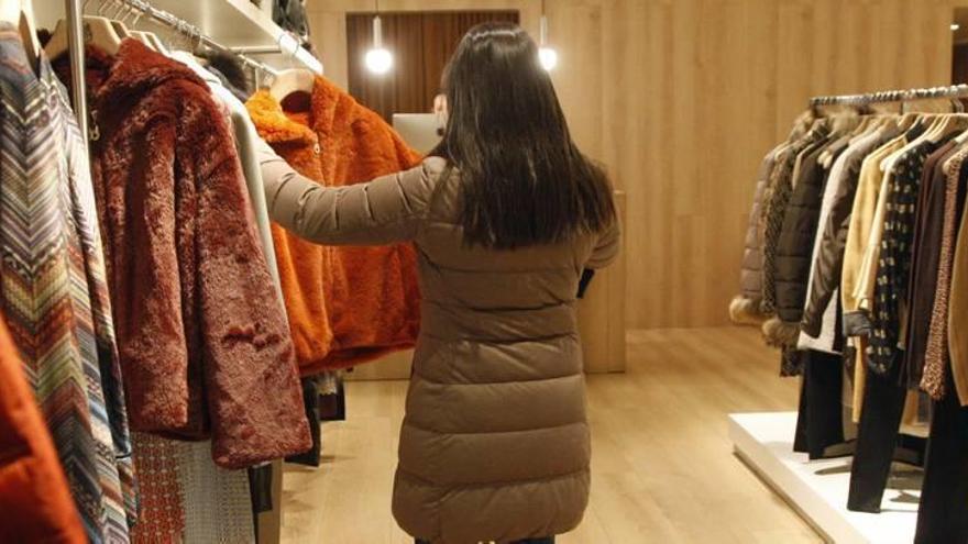 Una mujer busca, en una tienda de Murcia, un abrigo adecuado para afrontar el frío de estos días.