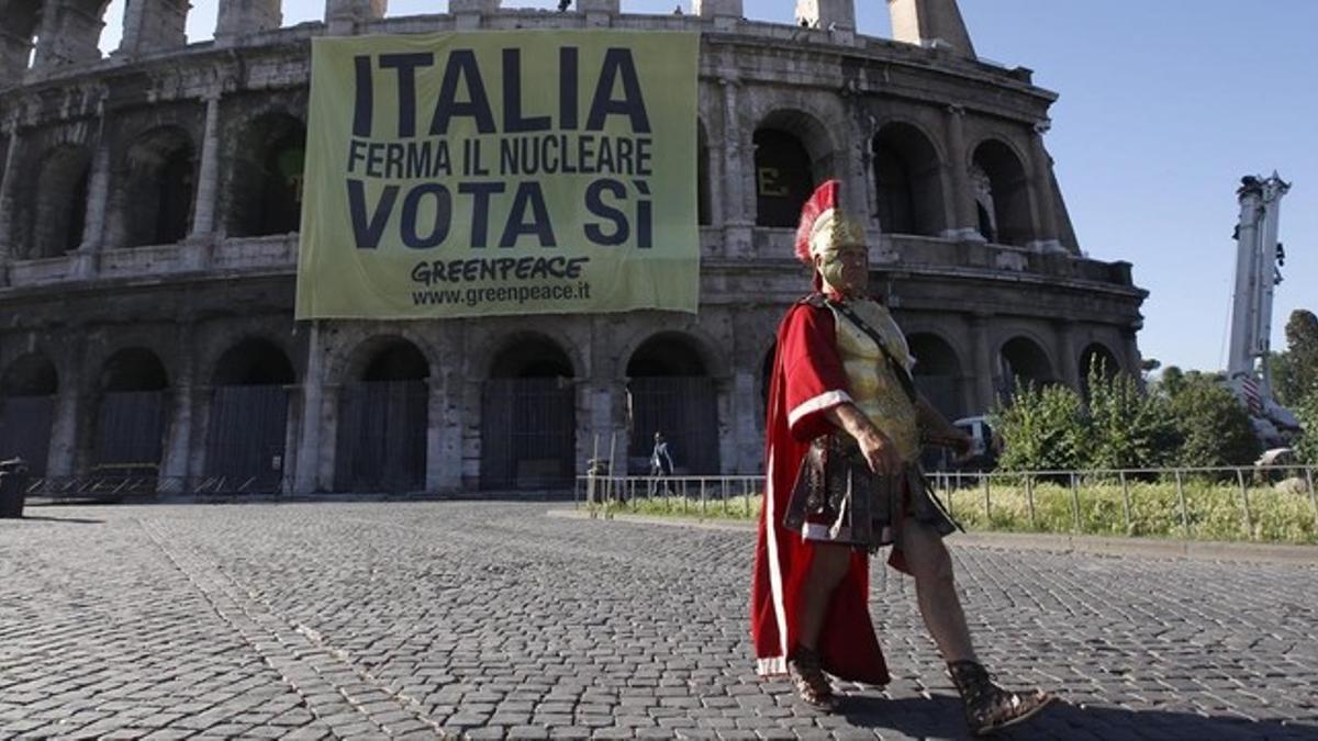 Un hombre vestido de centurión pasa frente al Coliseo romano.