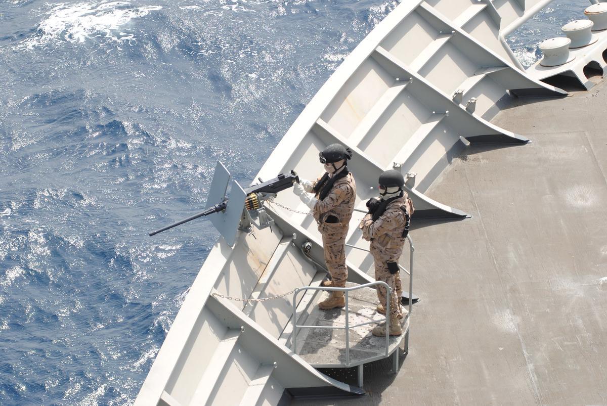 Dos miembros de la dotación del buque de asalto anfibio Galicia con la ametralladora que le sirve de defensa, en una travesía de la operación Atalanta