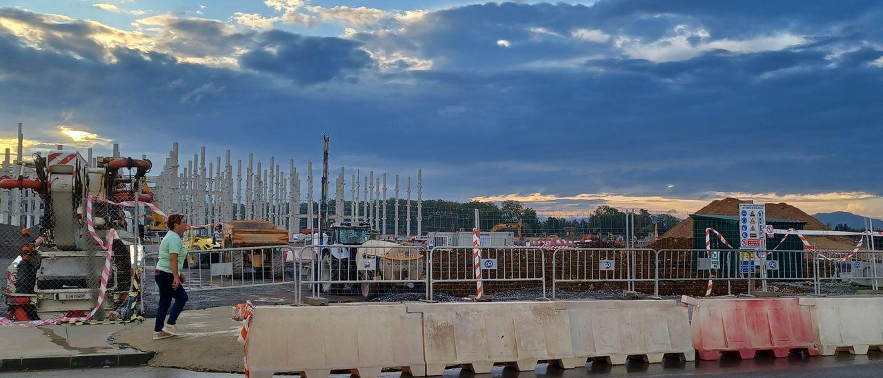 Una mujer, paseando en la zona de la obra de Amazon en Bobes, con los pilares de la gran nave al fondo