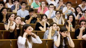 Un grup d’alumnes es recullen els cabells perquè el tribunal de les PAU comprovi que no porten auriculars amagats, aquest dilluns a la UAB.