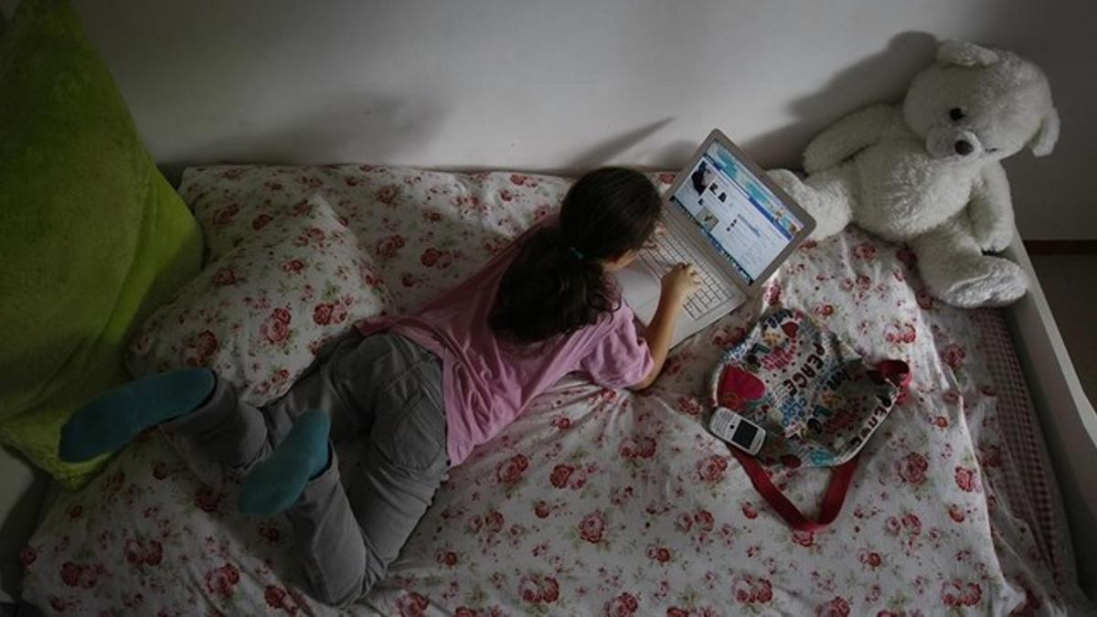 Una menor con un ordenador, en su habitación.