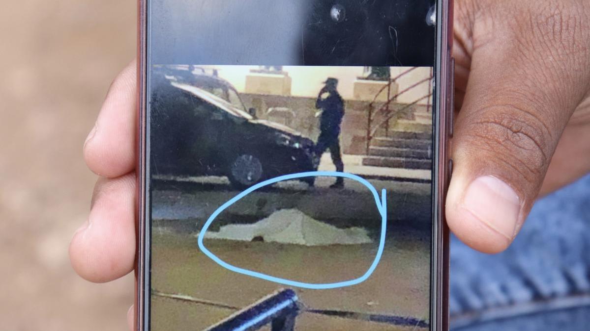 Un testigo muestra una fotografía del cadáver tendido en el suelo.