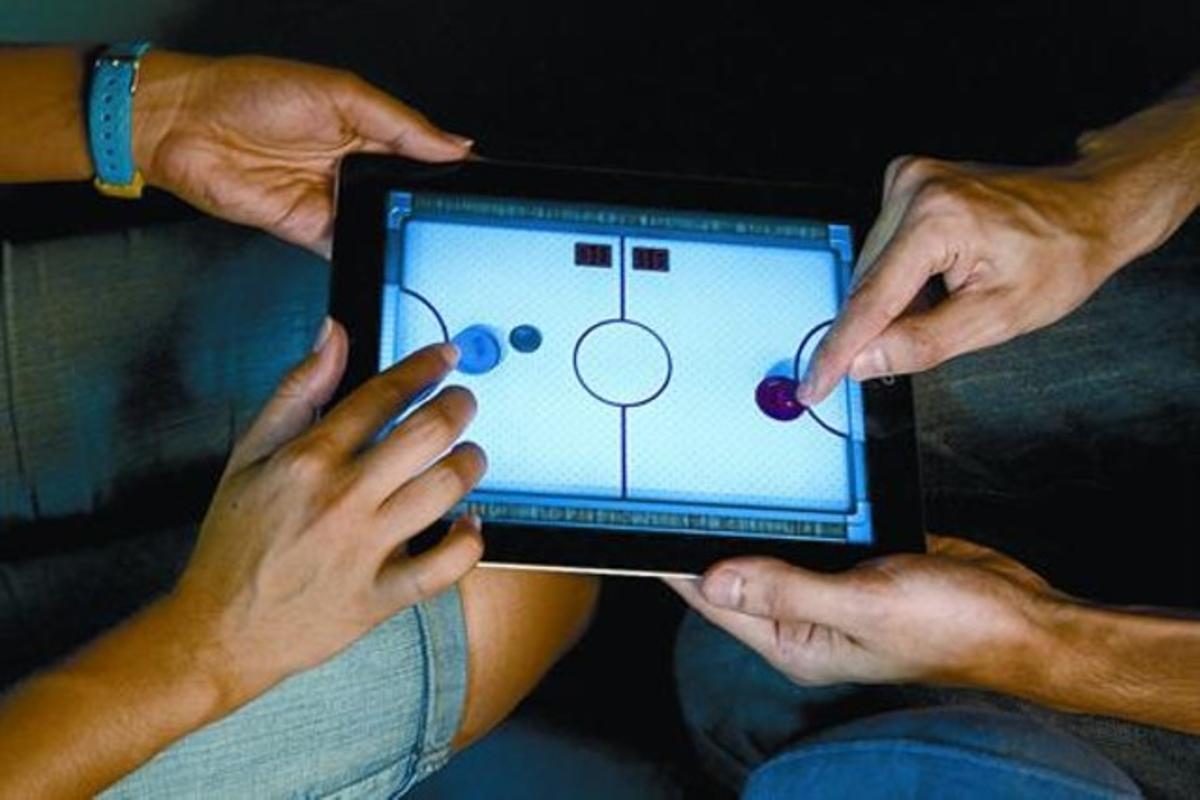 Dues persones juguen a l’iPad una partida d’hoquei d’aire.