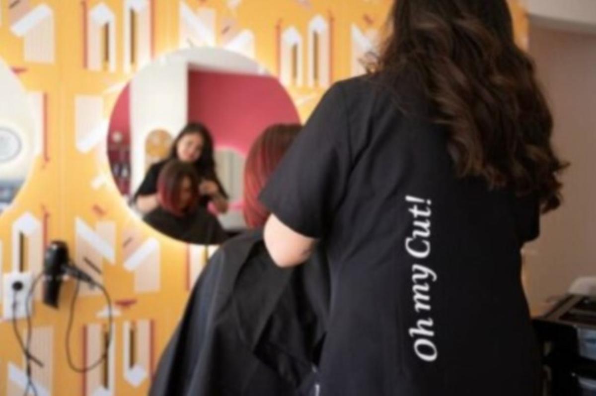 Una peluquera trabaja con una clienta en un local de Oh my cut!, una franquicia liderada por una mujer.