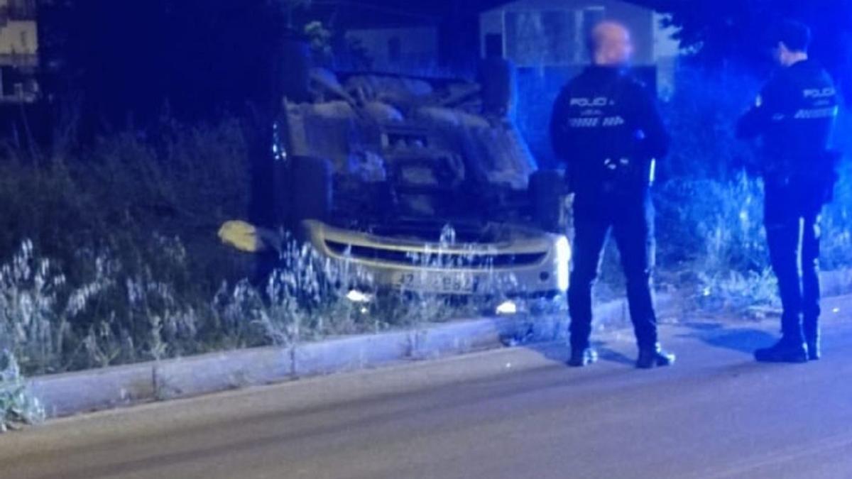 Dos policías junto al coche que volcó en un accidente la noche del lunes a la salida de Lucena.