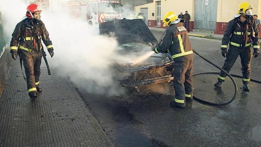 Los efectivos apagan las llamas del vehículo del que fue rescatado un joven en Santa Comba.  // G. Civil