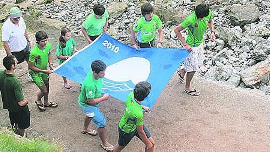 Miembros del club piragüista Los Gorilas trasladan la bandera azul hasta el lugar donde se llevó a cabo el izado.