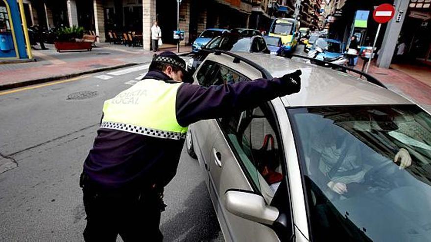 Un policía local de Benidorm informa a un conductor en una calle de la localidad.