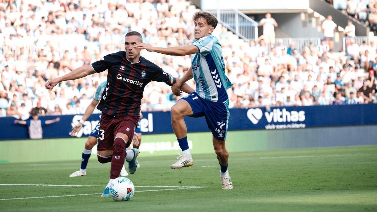 Disputa de un balón en el partido entre Málaga CF y SD Eibar.