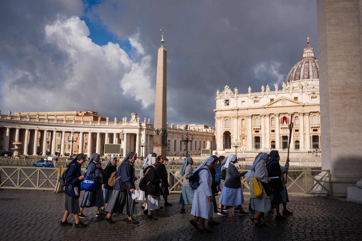 Nuns walk with a cross at St Peters Square, a day prior to the start of the conclave, in the Vatican on May 6, 2025. (Photo by Dimitar DILKOFF / AFP)