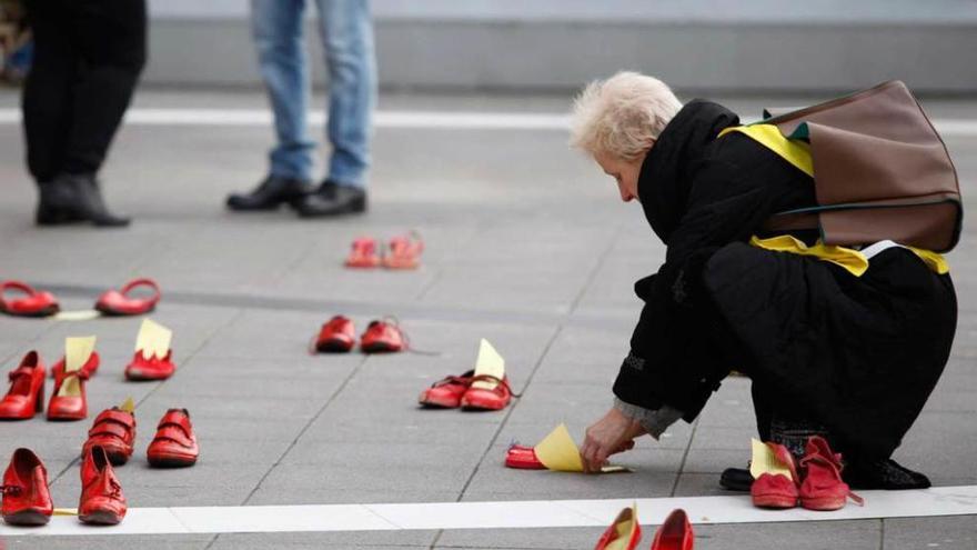 Una mujer coloca un par de zapatos en recuerdo de las víctimas de la violencia machista.