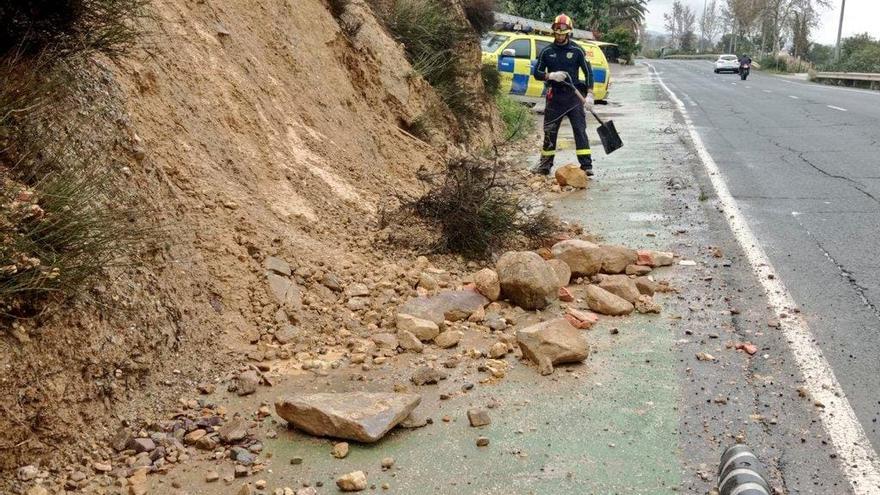 Un técnico de Protección Civil retira piedras y tierra de la carretera de La Parroquia.