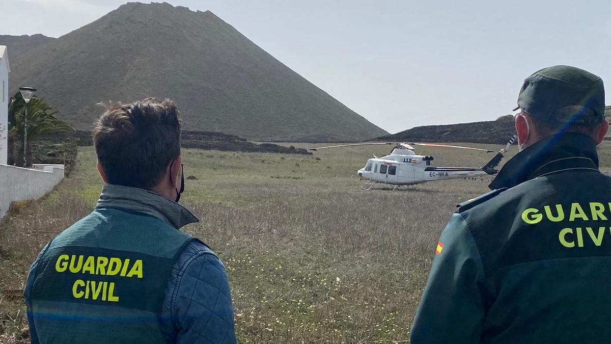 Dos guardias civiles observan el helicóptero del GES que participó en las labores de búsqueda del hombre fallecido en el Volcán de la Corona
