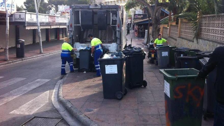 Operarios de Calvià 2000 retiran cubos de basura en una zona turística.