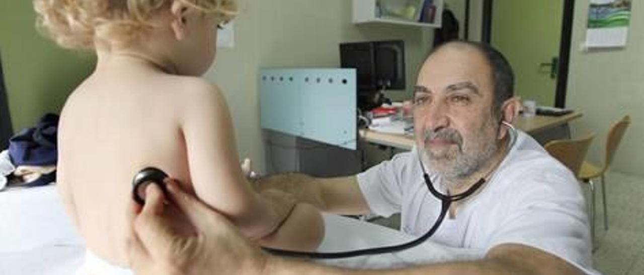 Un médico pediatra ausculta a un niño en la consulta.