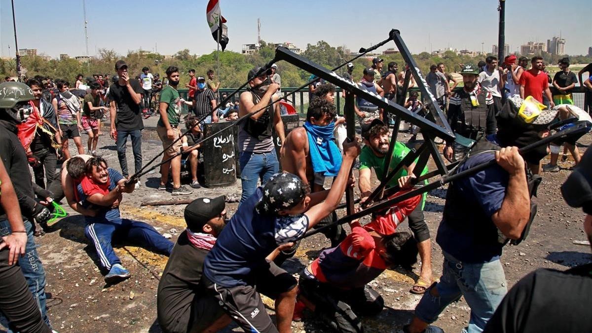 Manifestantes antigubernamentales utilizan una estructura metálica como catapulta para lanzar piedras a la policía, este domingo en Bagdad.