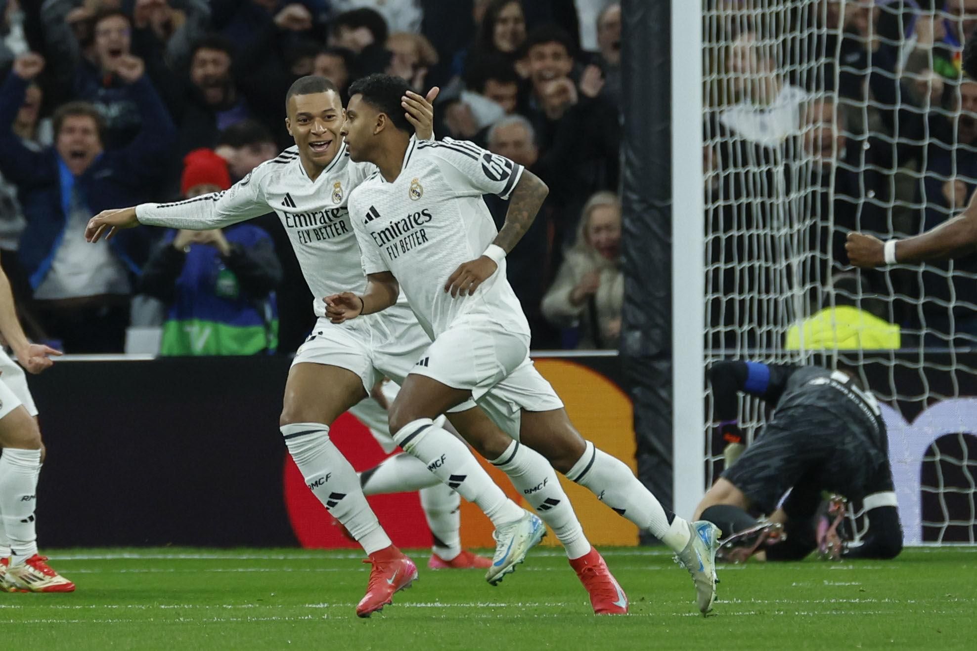 Los jugadores del Real Madrid, el brasileño Rodrygo (d) y el francés Kylian Mbappé, tras conseguir el primer gol del equipo madridista durante el encuentro correspondiente a la ida de los octavos de final de la Liga de Campeones que Real Madrid y Atlético de Madrid disputan en el estadio Santiago Bernabéu, en Madrid. EFE / Juanjo Martín.. (Real Madrid) (Atlético Madrid)