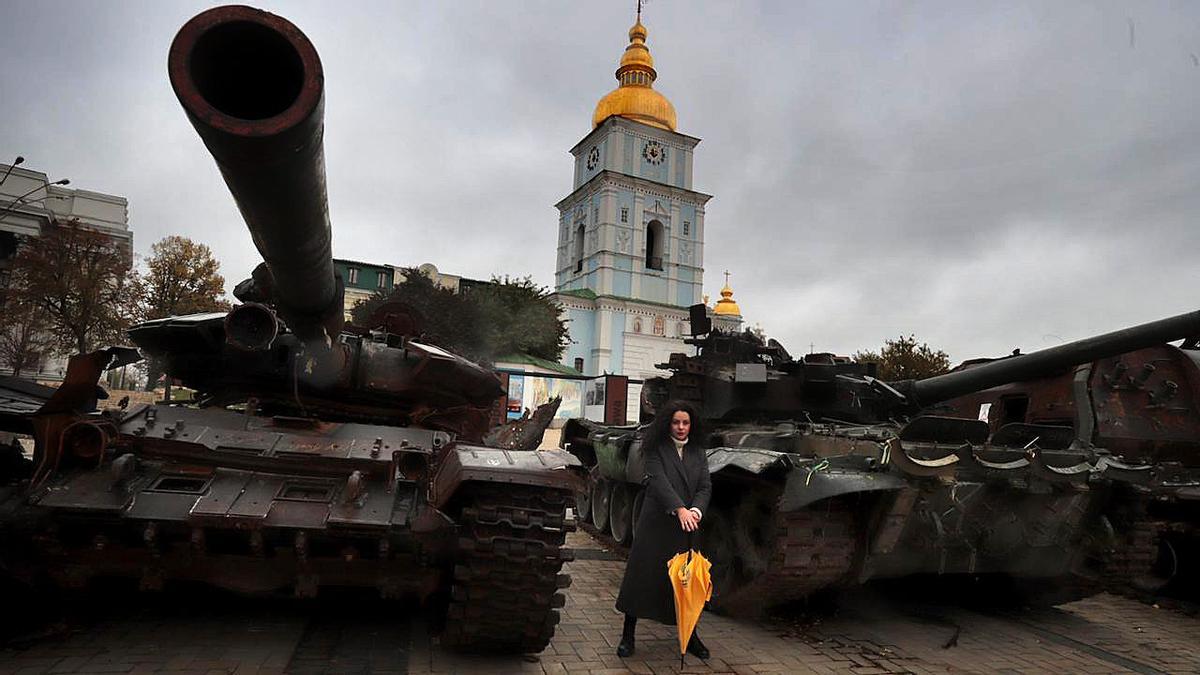 Olga Oibrova se fotografía frente a blindados y tanques rusos exhibidos frente a una iglesia de Kiev.