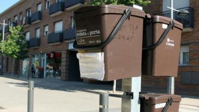 Cubells per a la recollida de la fracció orgànica penjats al davant d'un bloc d'habitatges de Celrà | ACN