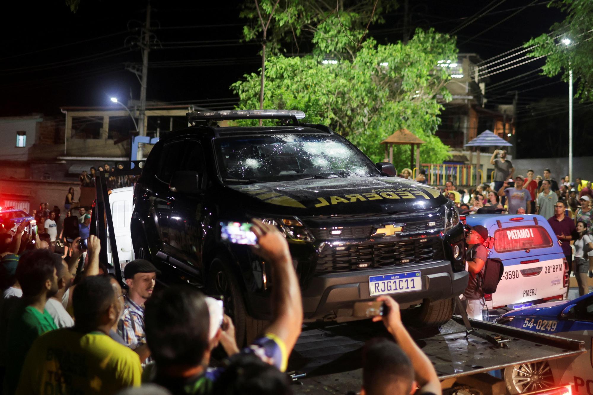 Varias personas toman fotos del vehículo policial dañado por Roberto Jefferson.