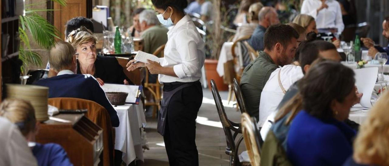 Una camarera atiende a dos clientes en un restaurante.