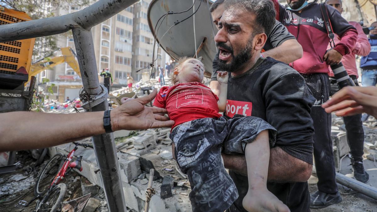 Un hombre porta el cuerpo de un niño herido tras uno de los bombardeos sobre Gaza.