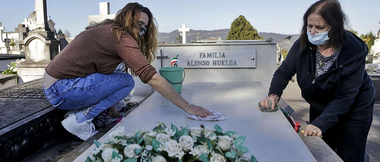 Sandra Rodríguez (izquierda) y su madre, Paquita Ortiz, ayer, limpiando el sepulcro de su padre y marido en el cementerio del Salvador. | Julián Rus