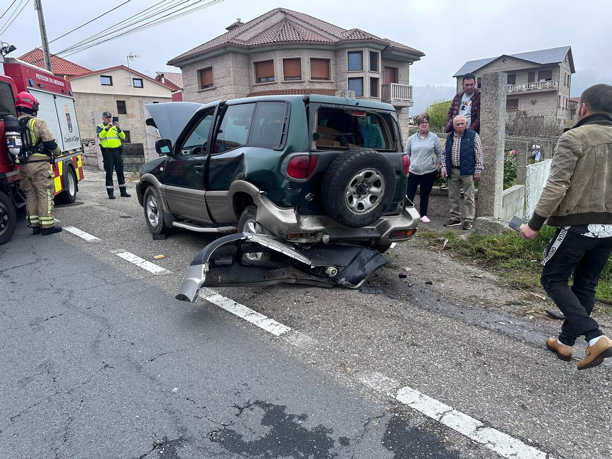 Equipos de emergencias y vecinos observan en coche que fue alcanzado.