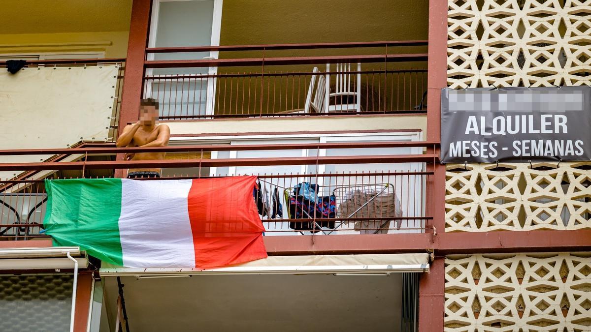 Un joven se asoma al balcón de un edificio donde se alquilan viviendas vacacionales.