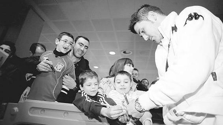 David Villa firma autógrafos a jóvenes aficionados a su llegada al aeropuerto de Asturias.