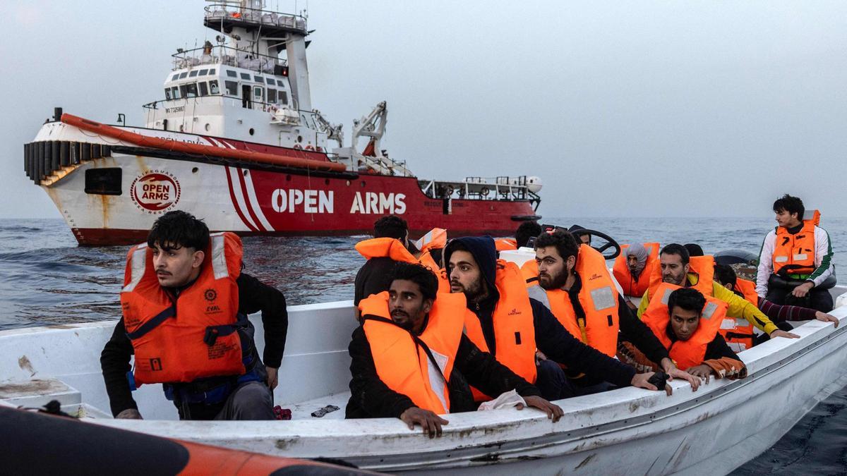 Migrantes procedentes de Siria y Bangladesh son asistidos el 18 de enero de 2024 por un equipo de rescate de la ONG española Open Arms , frente a las costas libias, en aguas internacionales del Mediterráneo central. El equipo de rescate socorrió a 52 hombres y 5 niños, procedentes de Siria, Bangladesh, Pakistán y Egipto, que navegaban a bordo de tres pequeñas embarcaciones de madera en aguas internacionales. (Foto de Santi Palacios/AFP)