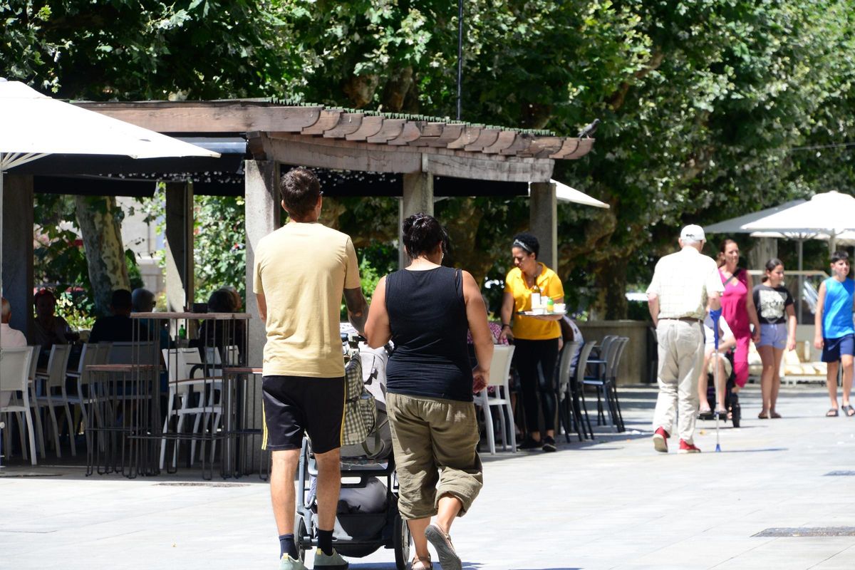 Una pareja pasea por el centro de Cangas con un carrito de bebé.
