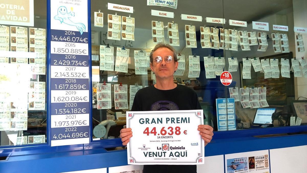 Un treballador de l’Anxova Milionària amb el cartell corresponent al premi de la Quiniela